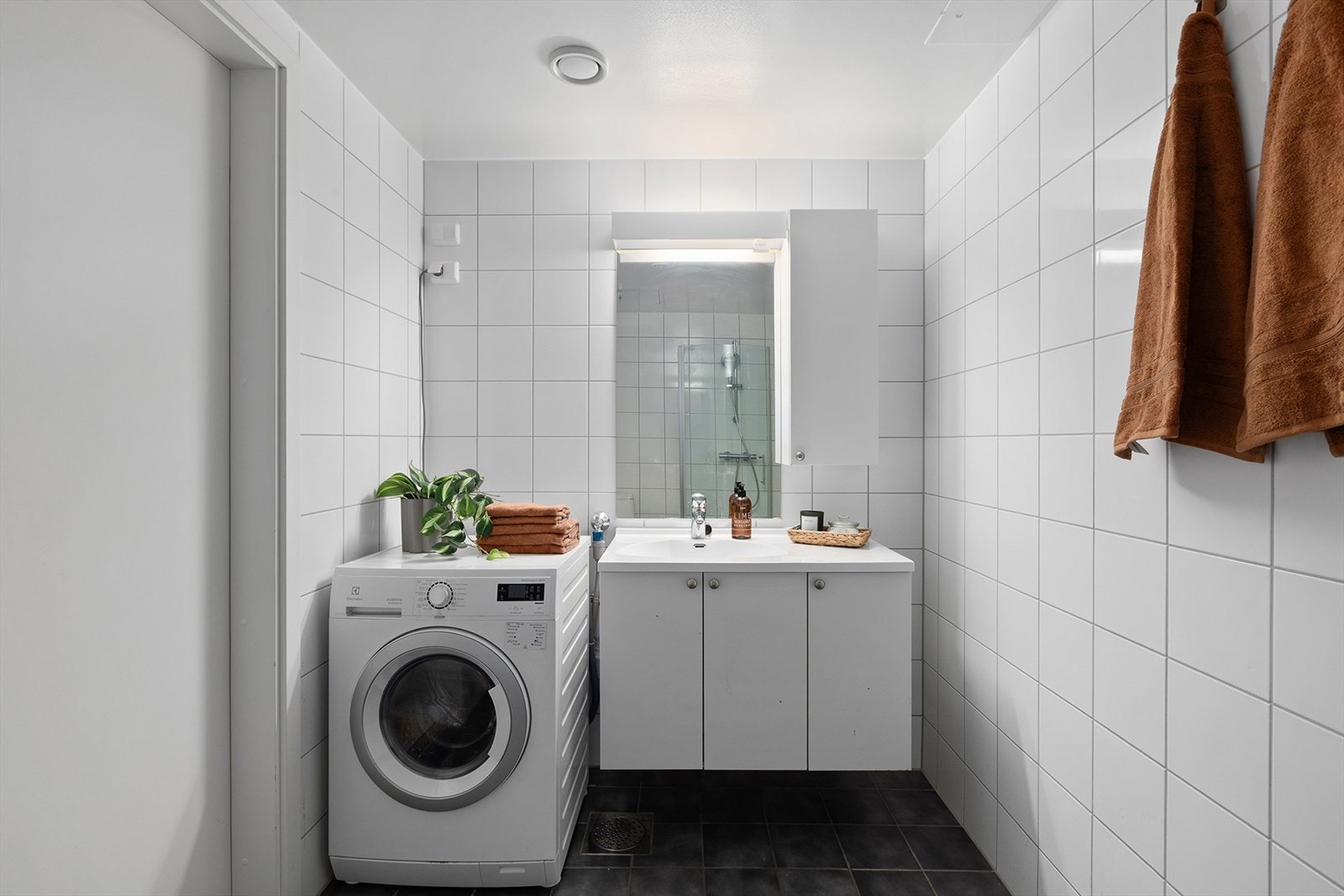 Servant med baderomseksjon, speil med belysning, veggskap og opplegg for vaskemaskin. Galleribilde