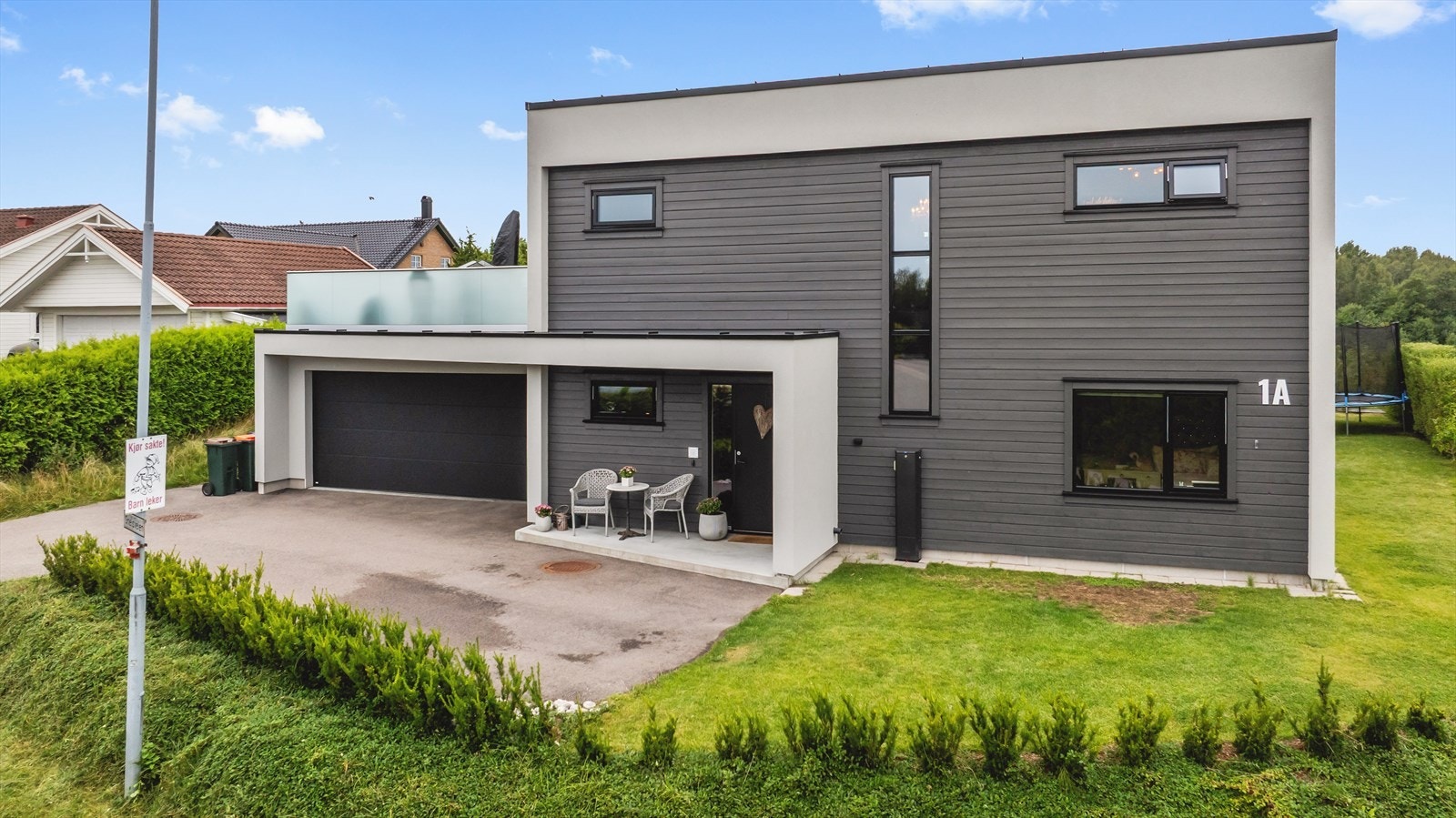 Det er parkering i en integrert dobbelgarasje med direkte inngang til huset - her går man tørrskodd inn i all slags vær. I garasjen er det opplegg for elbillader. Gårdsplassen er asfaltert med plass for flere biler. Galleribilde