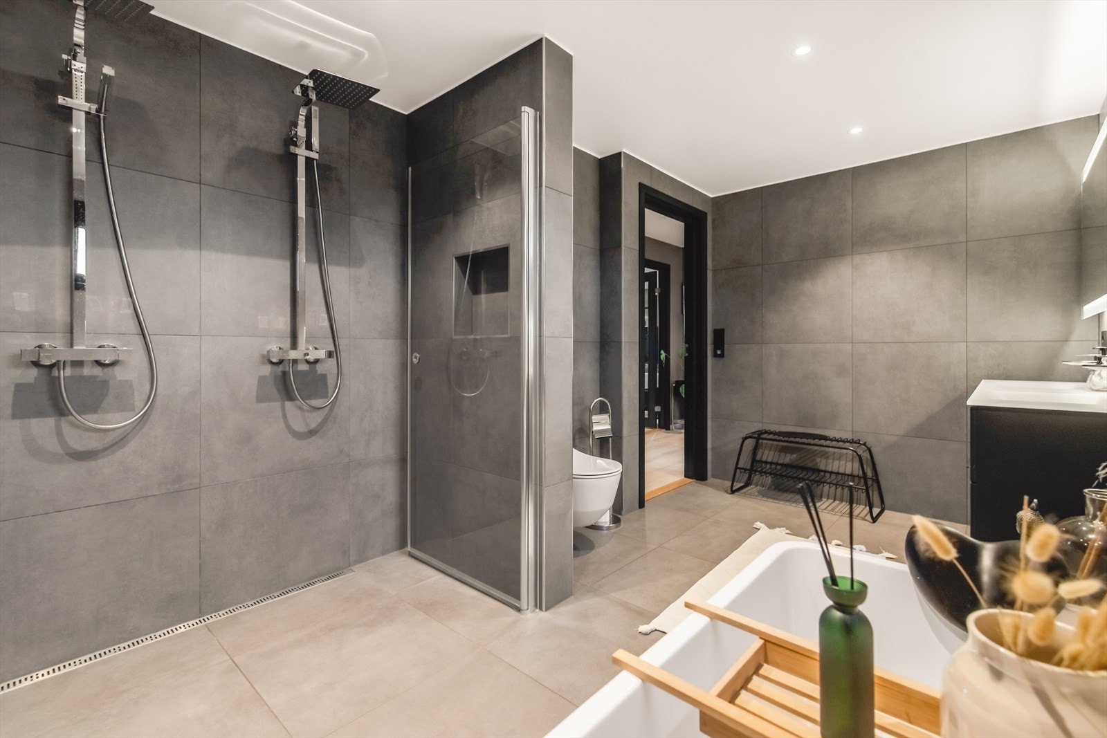 Badet oppe er luftig med en harmonisk spafølelse. På badet er det både en stor dusjnisje og et deilig badekar med dusjløsning, der førstnevnte har slukrenne, dobbel regnfallsdusj, innfellbare glassdører og egen nisje for hygieneartikler. Galleribilde