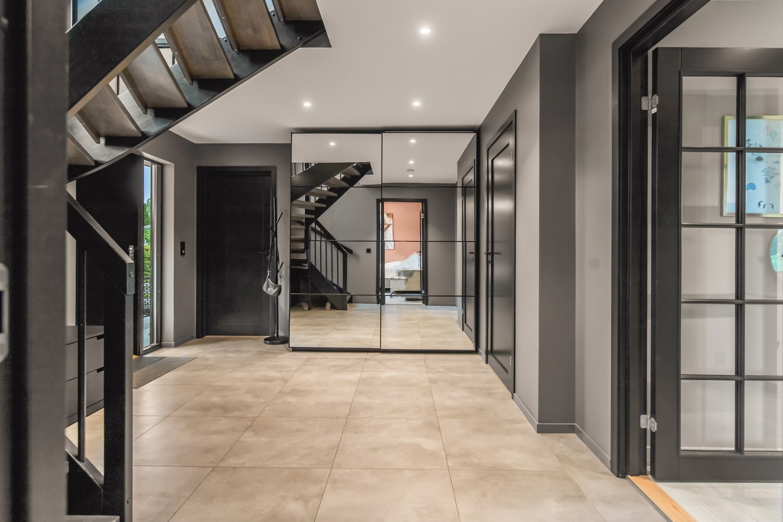 Entreen har god størrelse, og yttertøyet ryddes enkelt bort i en stor skyvedørsgarderobe med speilfronter. I huset er de fleste detaljer som stikk, brytere og karmer holdt i sort - stilrent, delikat og gjennomført. Galleribilde