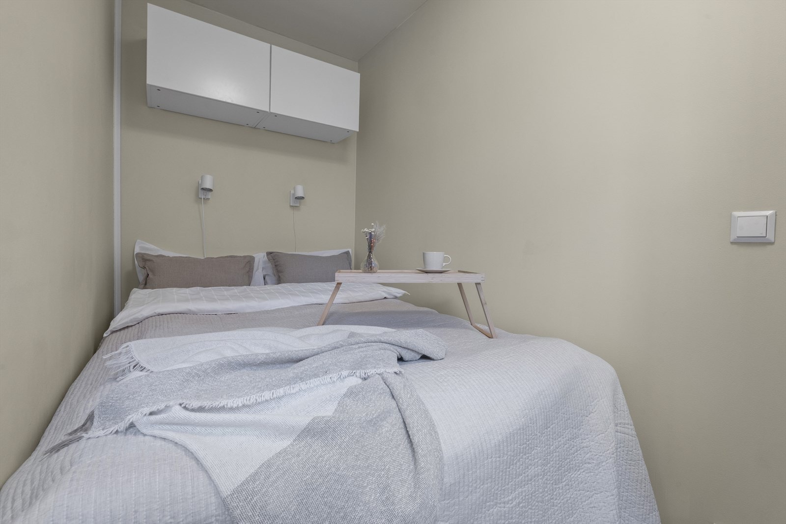 Her har selger en seng som er 140 cm. bred. På veggen over sengen er det satt opp lamper og skap for oppbevaring. Galleribilde