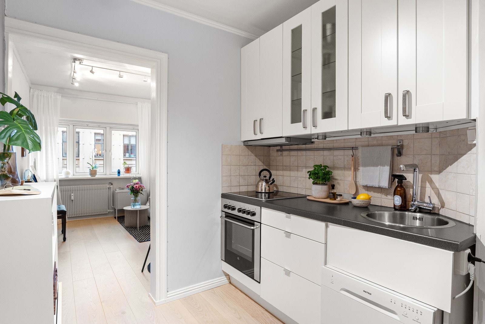 Lyst og innbydende kjøkken med integrerte hvitevarer som platetopp, stekeovn og kjøle/fryseskap. Galleribilde