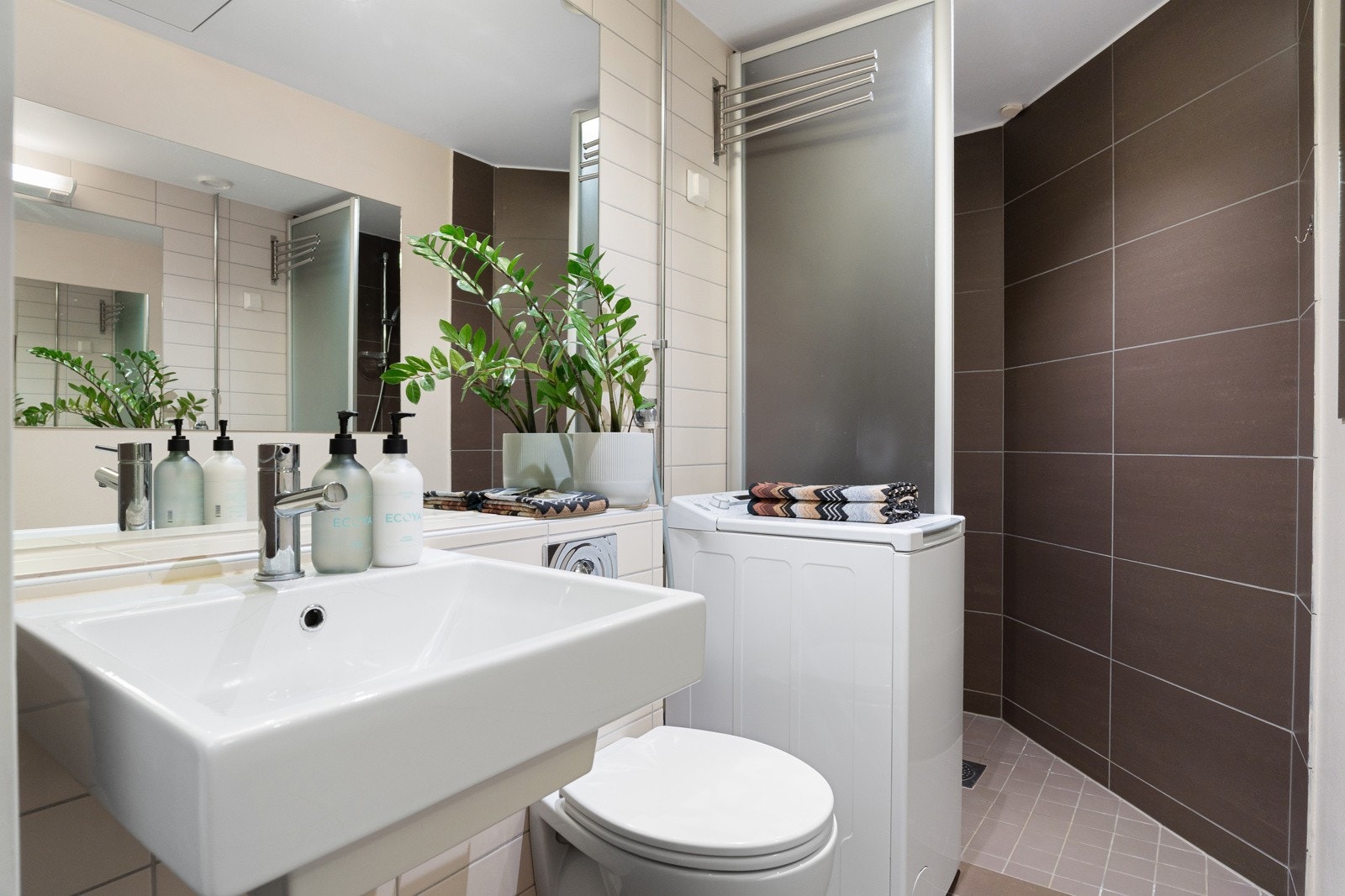 Innredningen består av veggehengt toalett, servant med speil og lysarmatur, opplegg for vaskemaskin og et praktisk dusjhjørne med glassvegger og termostatstyrt blandebatteri. Galleribilde