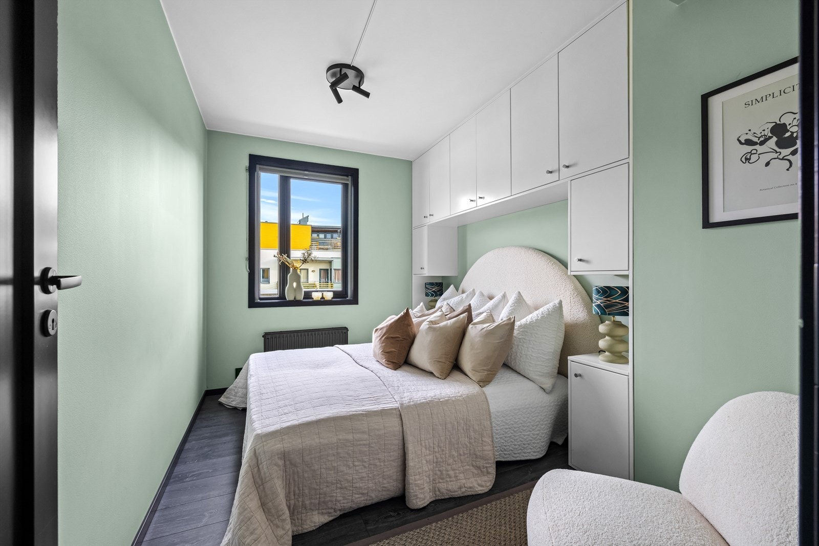 Lyst soverom med smart oppbevaringsløsning og faste skap over sengen. Galleribilde