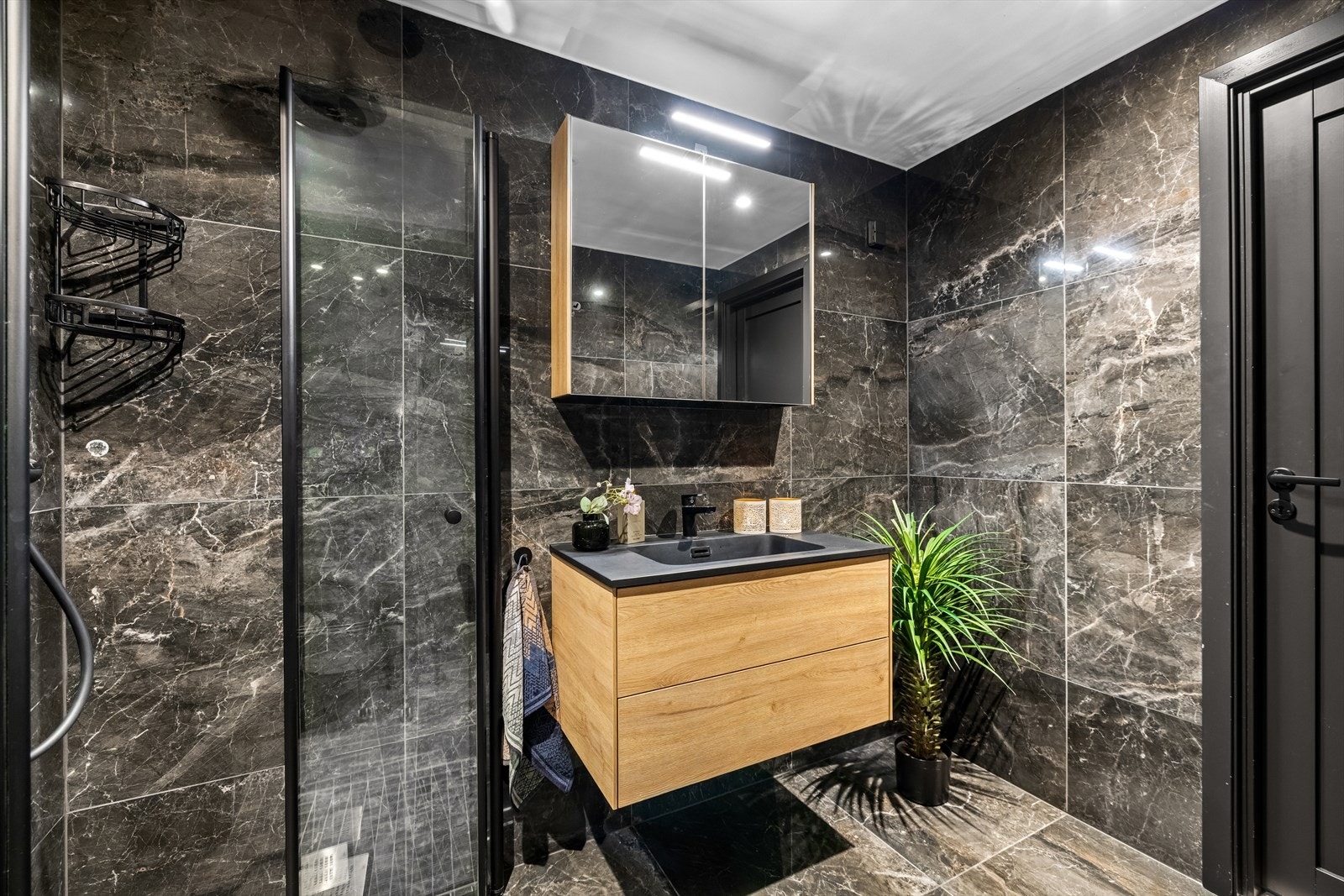 Dusjhjørne med foldedører, vegghengt toalett og servantskap med oppbevaringsplass. Galleribilde