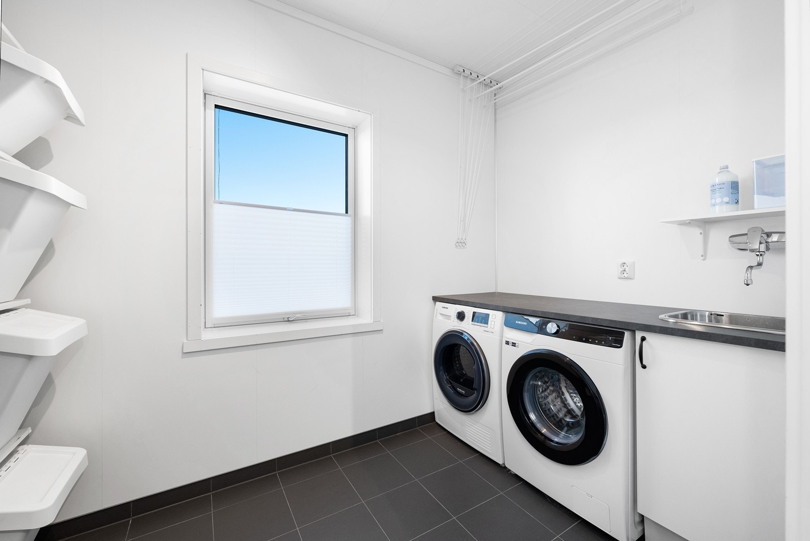 Flott og praktisk innredet vaskerom med god plass for både vaskemaskin og tørketrommel, brettebenk med utslagsvask samt rikelig med klesoppbevaring. Galleribilde