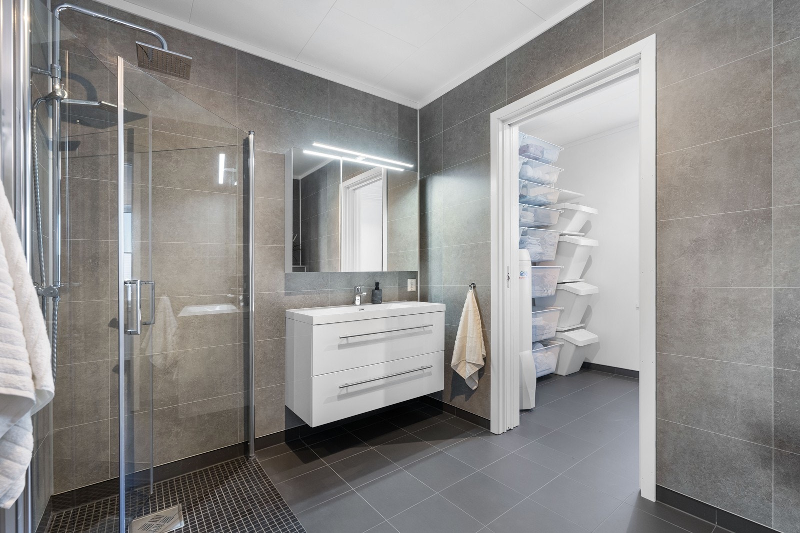 Her har man innredning som dusjhjørne, vegghengt wc og flott moderne servantinnredning med skuffer og speilskap. Det er direkte inngang fra badet til vaskerom. Galleribilde