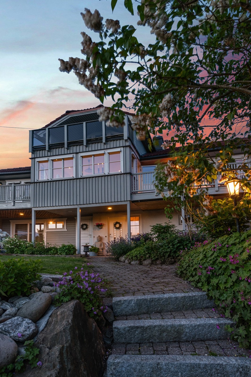 Fra gårdsplassen fører steintrapp og gangsti til overbygd inngangsparti med to separate ytterdører. Galleribilde