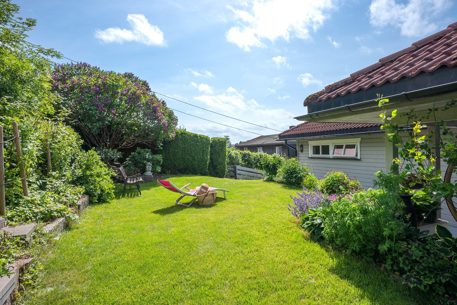 Hagen oppleves frodig og skjermet med trær, busker, hekk, bed, gressplen og div. beplantning. Galleribilde