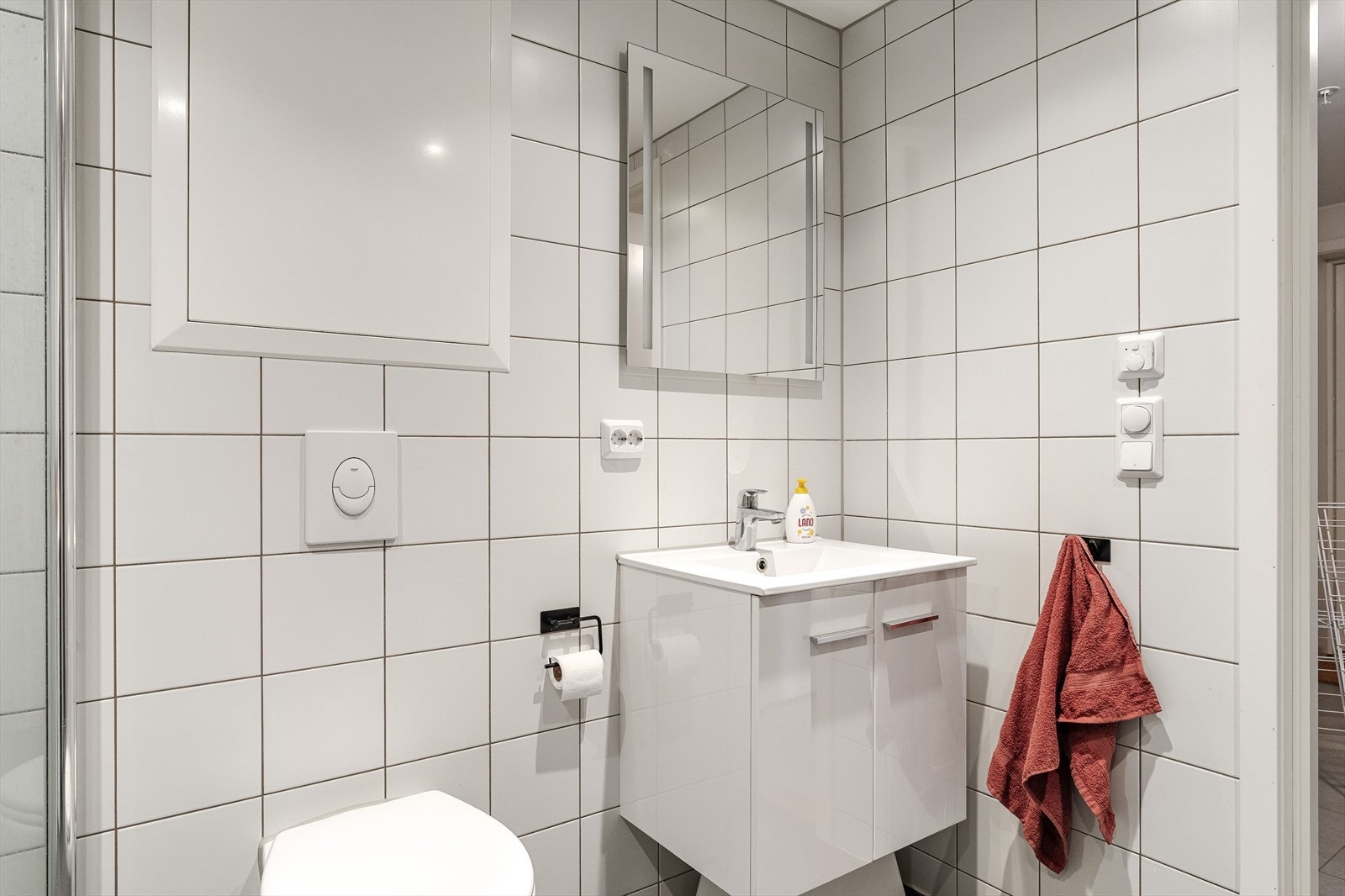 Badet har opplegg for vaskemaskin, innfellbare dusjdører, vegghengt toalett, lysspeil og servantskap. Galleribilde