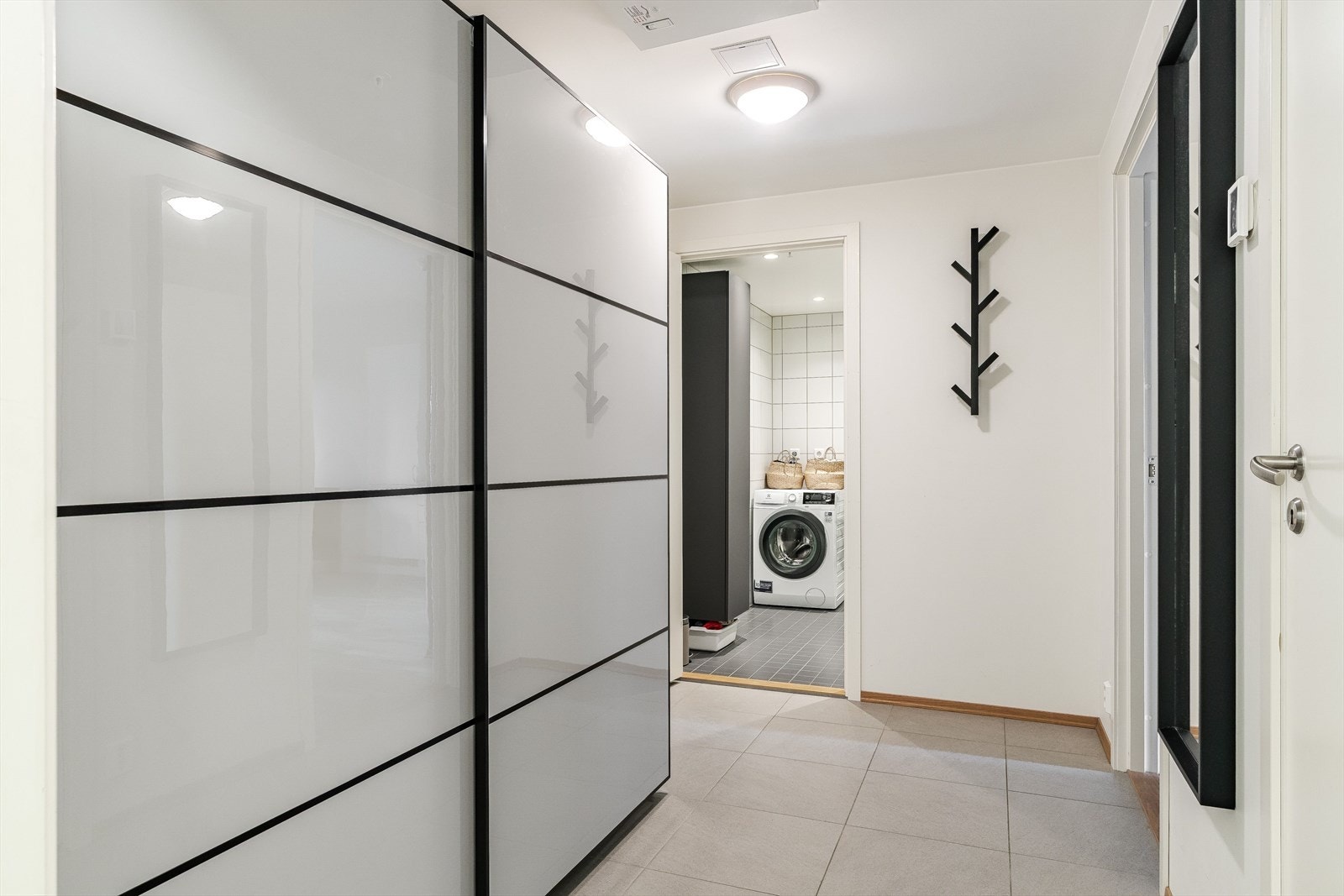 Entré med flislagt gulv og romslig skyvedørsgarderobe som gir gode oppbevaringsmuligheter. Galleribilde