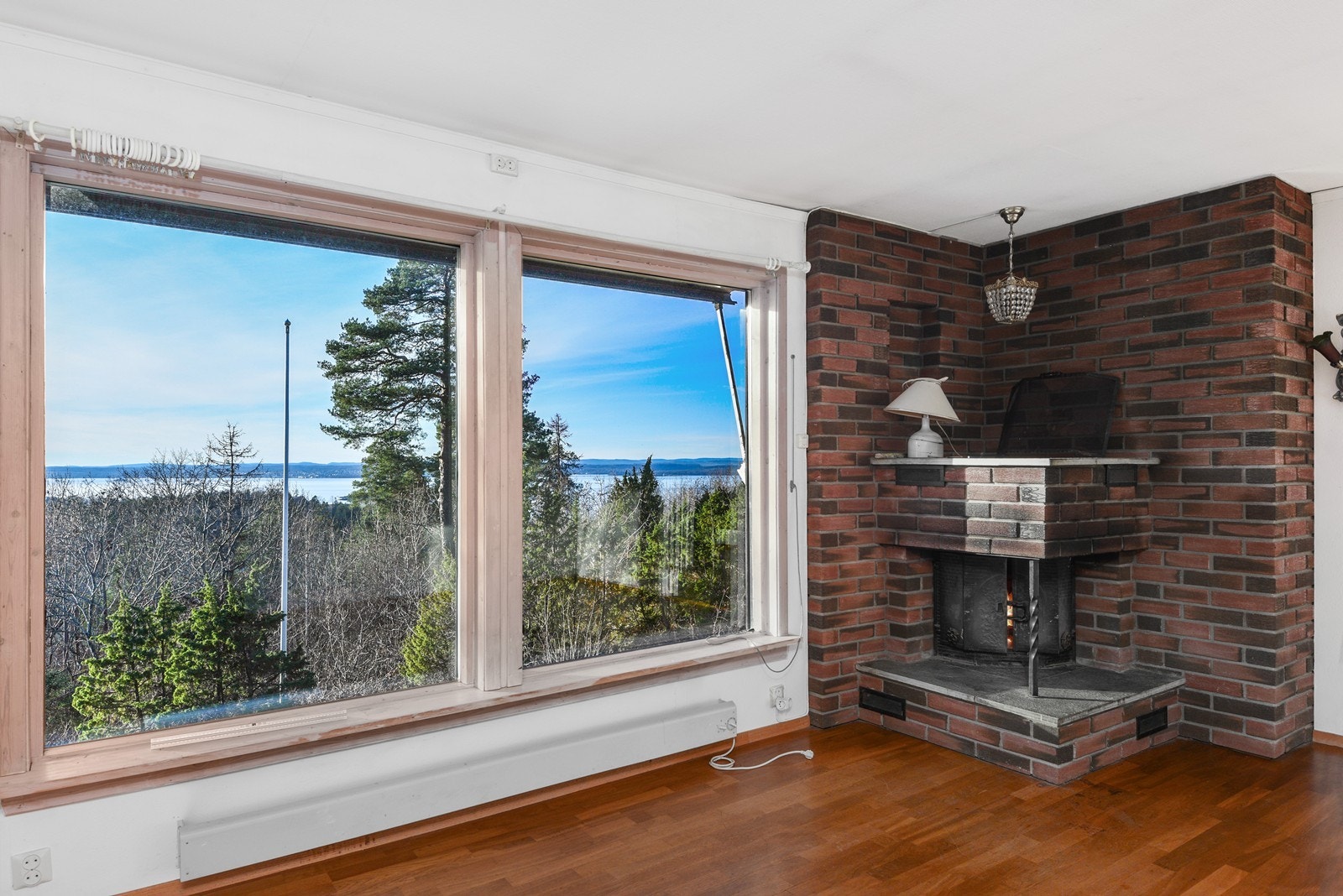 Stuen har utsyn mot fjorden og en klassisk teglstenspeis plassert i hjørnet. Galleribilde