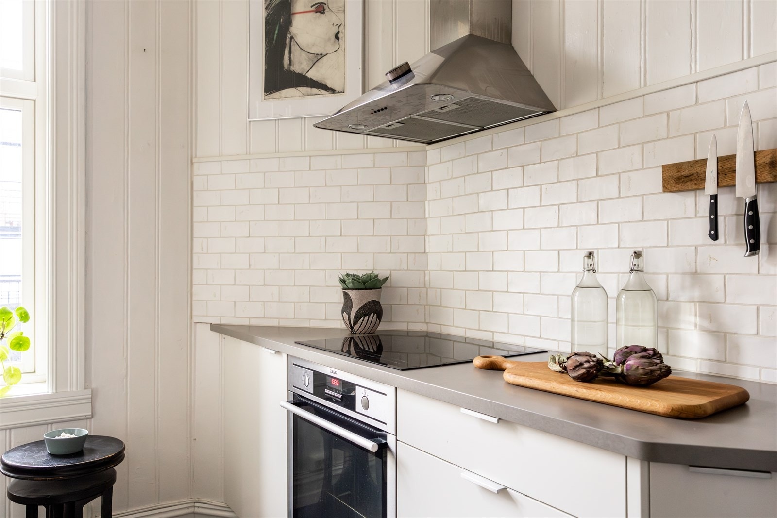 - Benkeplaten er i stein med mørk overflate, og det er montert nedfelt platetopp og oppvaskkum i svart utførelse. Veggen over benken er flislagt - Galleribilde