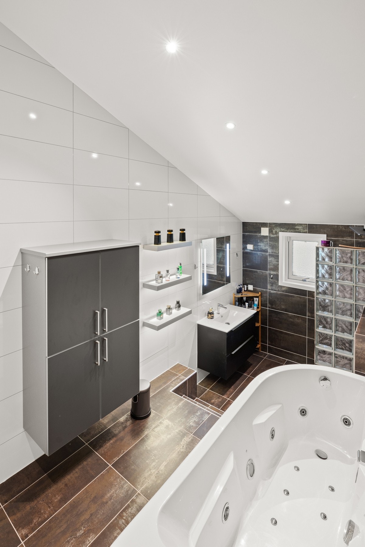 Badet har et romslig boblebadekar som er plassert på det høyere plattå, noe som gir en følelse av spa-luksus i hjemmet Galleribilde