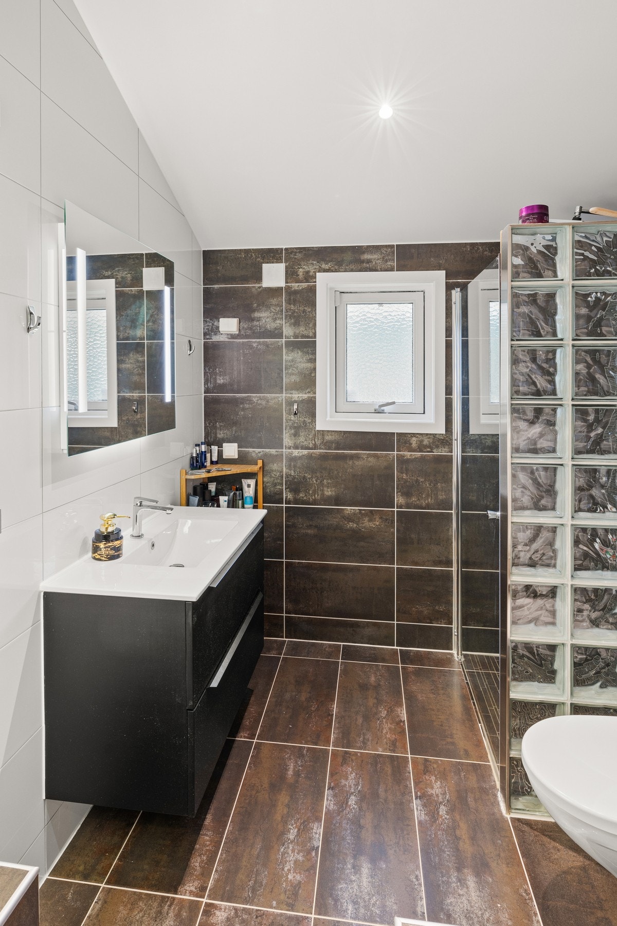 Badet er helfliset fra gulv til tak med moderne, stilrene fliser som gir en luksuriøs atmosfære Galleribilde