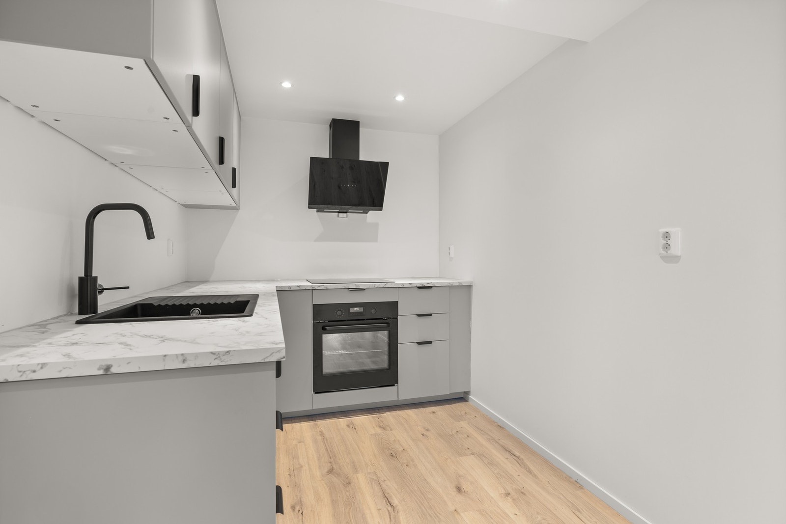 Nedfelt komposittkum med sort armatur setter et stilfullt preg på løsningen. Kjøkkenet er godt utstyrt med integrerte hvitevarer, inkludert induksjonstopp, stekeovn og smal oppvaskmaskin. Galleribilde