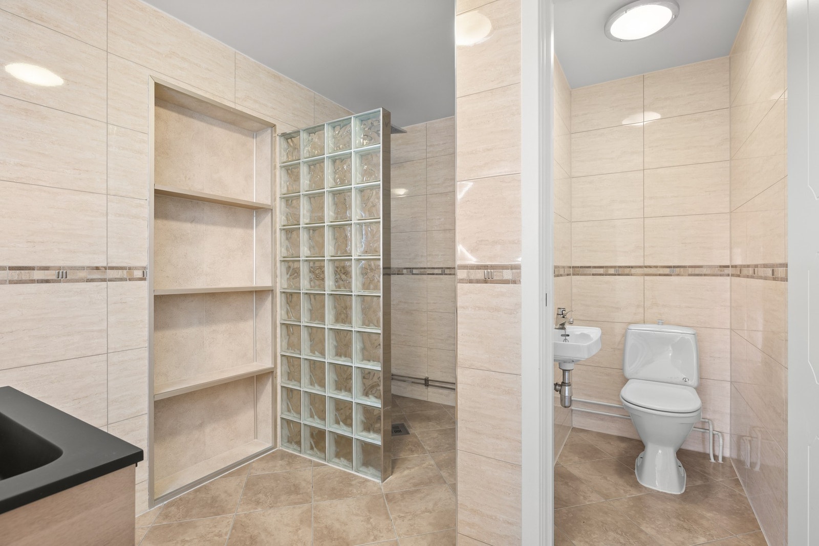 Badet er utstyrt med servantinnredning med skuffer og sort servant med tilhørende ettgrepskran, begge nytt fra 2025. Galleribilde