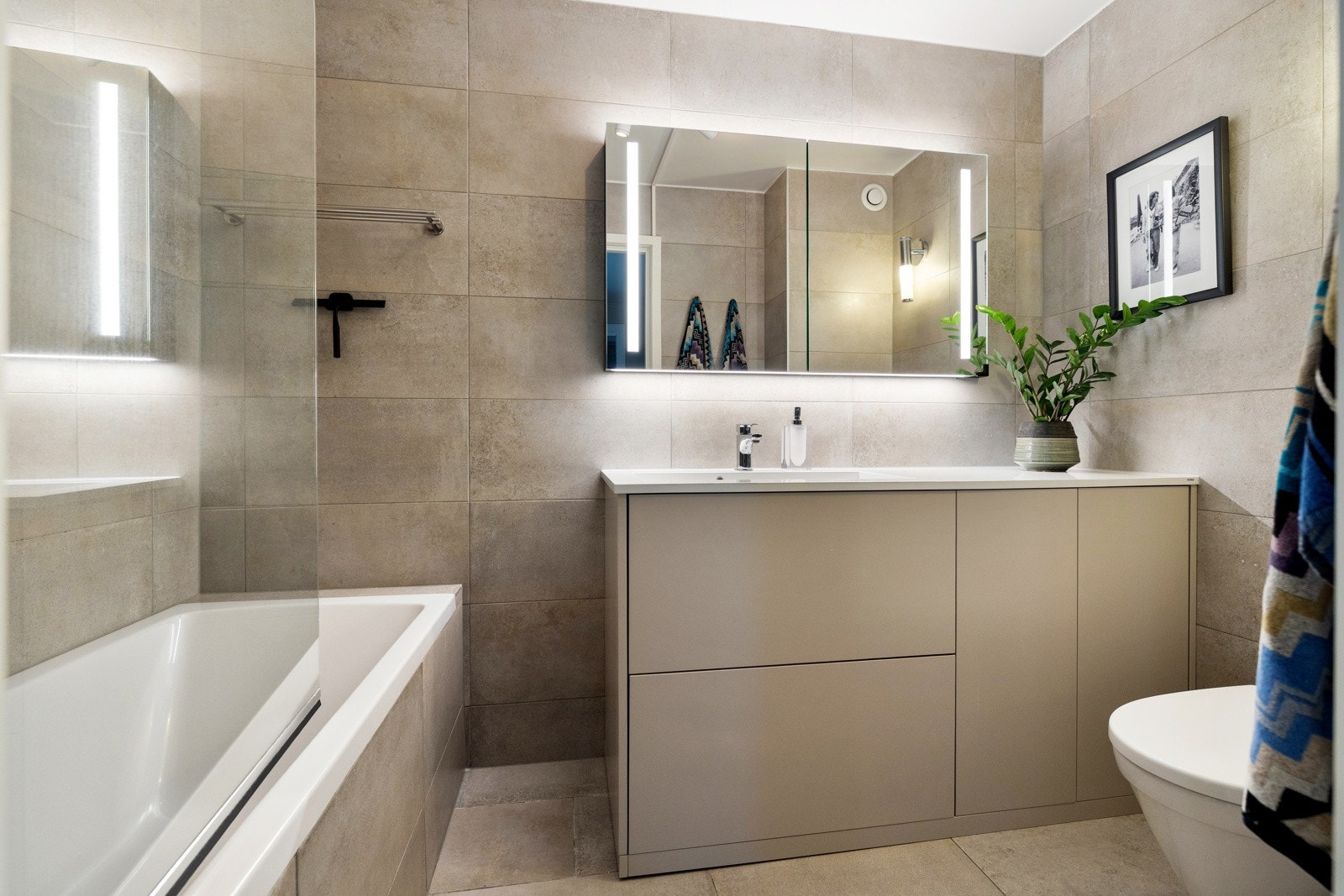 Hovedbadet har adkomst fra kjøkkenet. Badet har store lyse fliser med gulvvarme Galleribilde