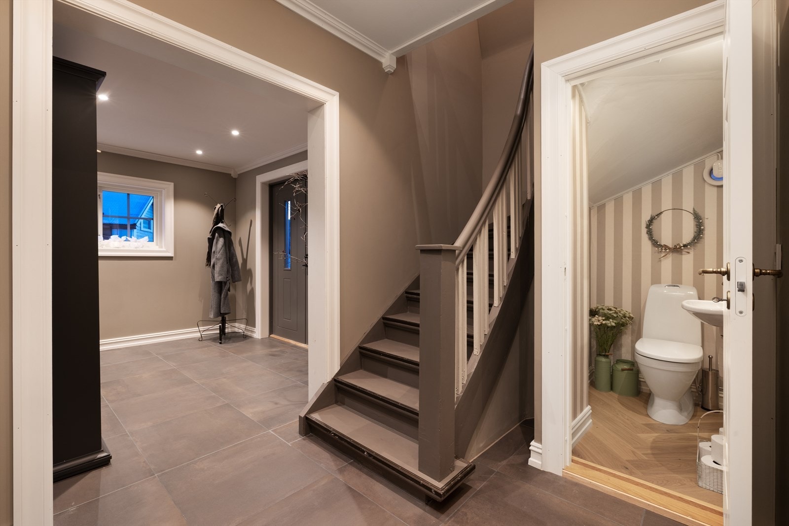 Trappeadkomst til boligens øverste plan. Stilrent toalettrom i hovedetasjen, praktisk plassert under trappen. Galleribilde