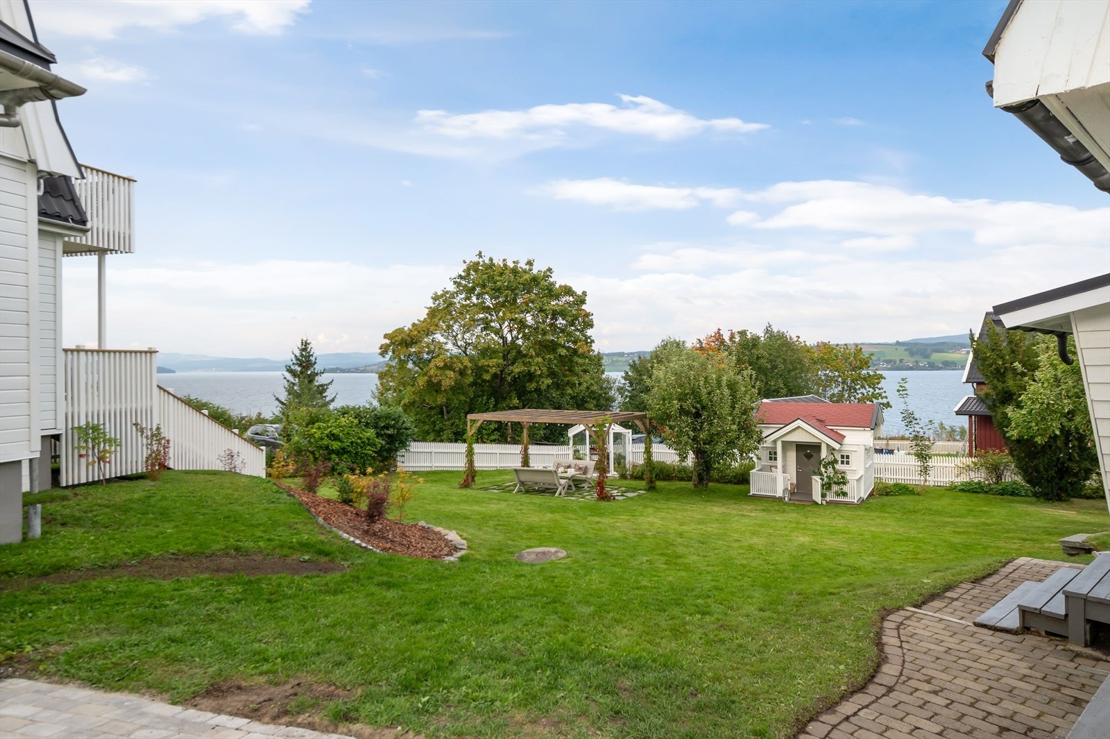 Hagen er omkranset av hvitmalt gjerde som gir trygghet og et helhetlig uttrykk, og utsikten mot Mjøsa setter prikken over i-en. Galleribilde