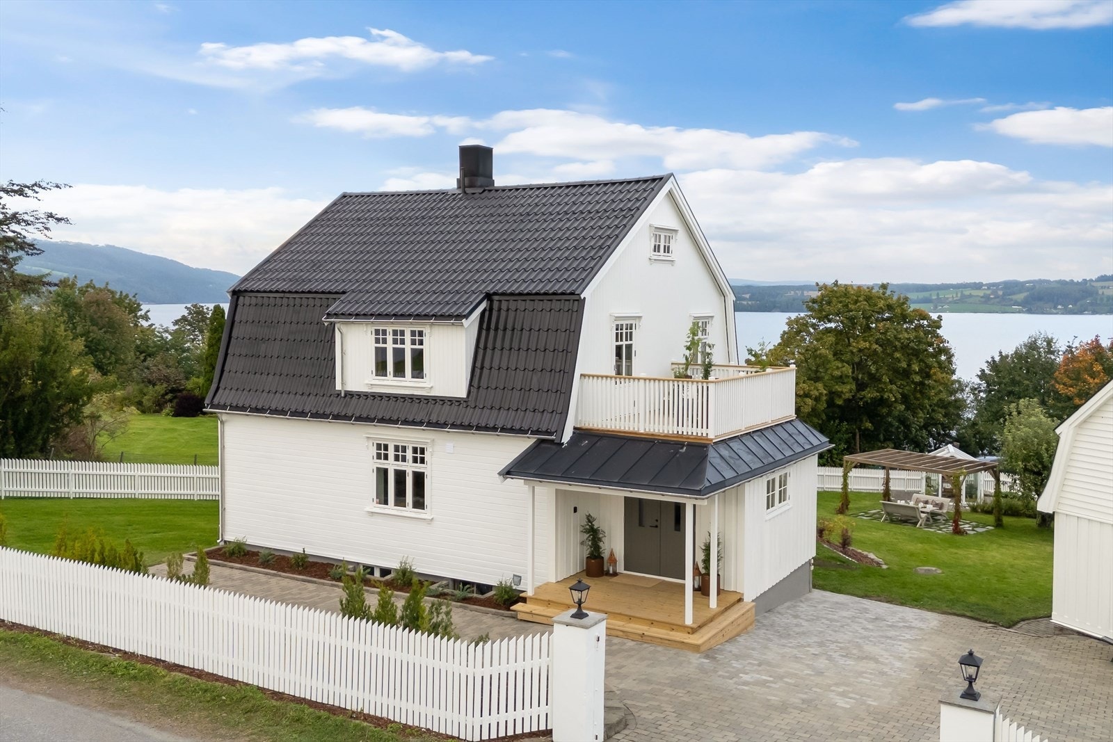 Steinbelagt gårdsplass og hvitt gjerde gir et rent og ryddig uttrykk. Galleribilde