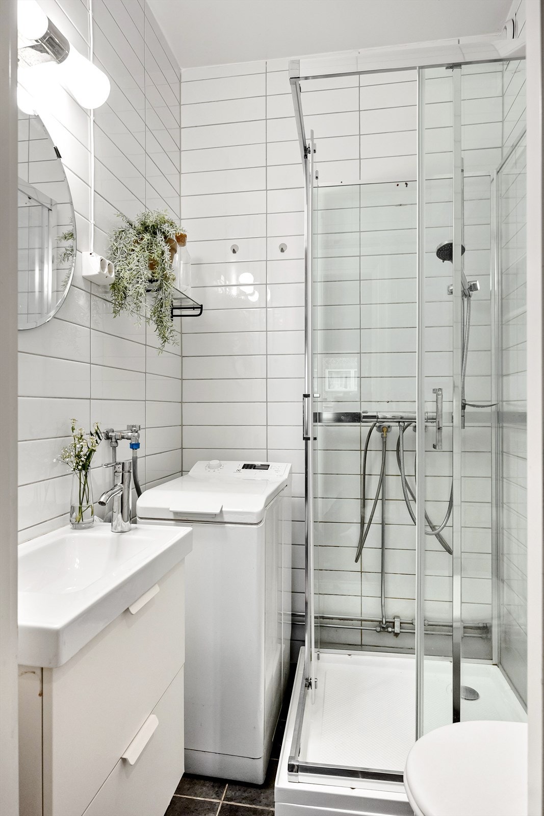 Tidløst flislagt baderom med dusjkabinett og opplegg for vaskemaskin. Galleribilde