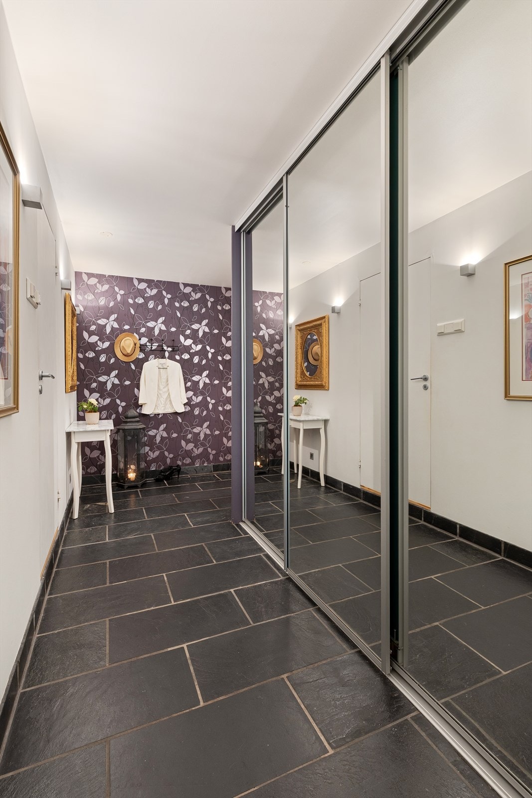 Romslig entré med skyvedørsgarderobe og flislagt gulv for enkelt vedlikehold. Galleribilde