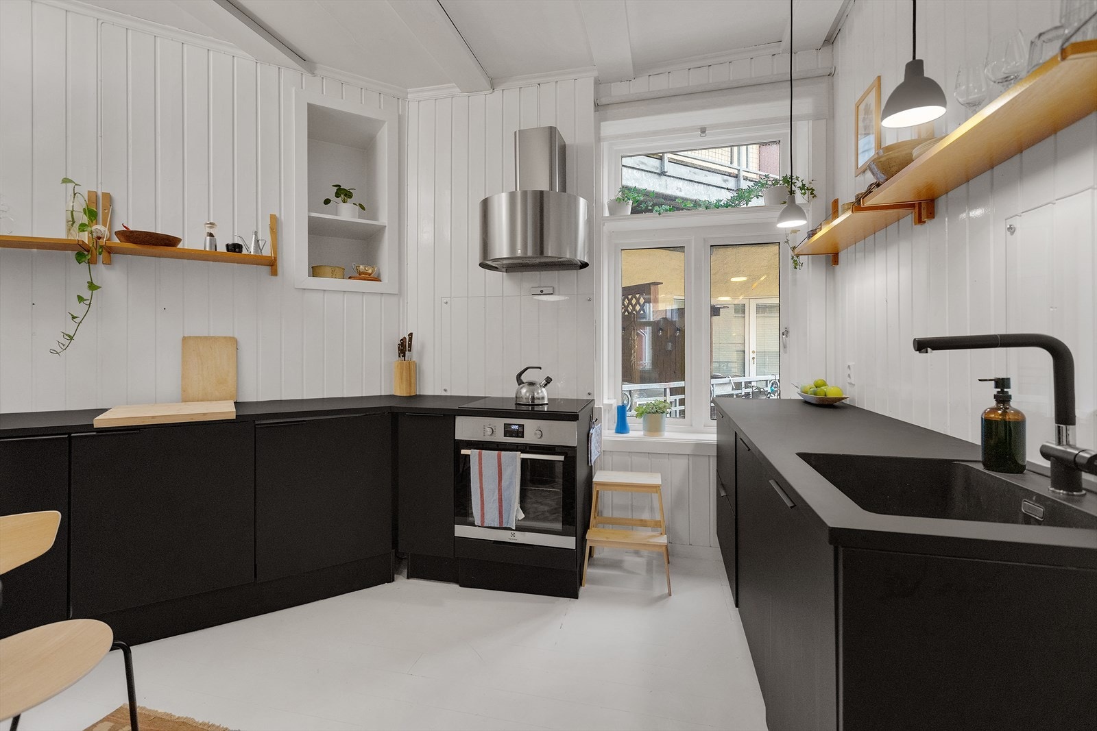 Stilrent kjøkken med integrerte hvitevarer og vedovn som blikkfang Galleribilde