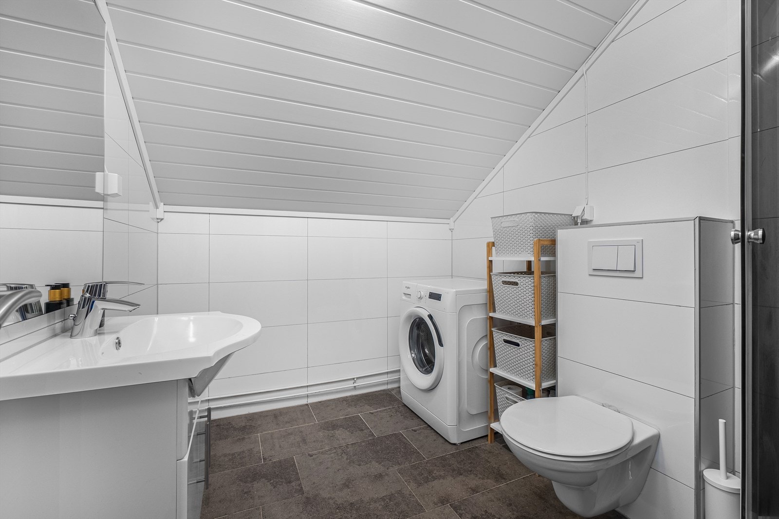 Lyst bad med flislagt gulv med varme, innredning, vegghengt wc, dusjkabinett og el-vifte i tak Galleribilde