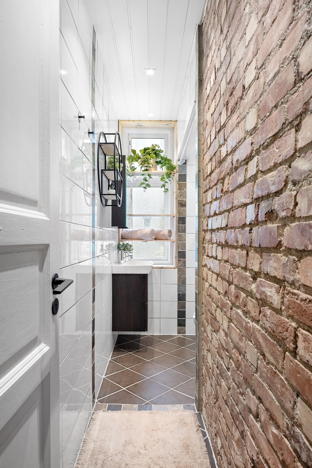 Delikat bad med flotte fliser og teglsteinsvegg. Galleribilde