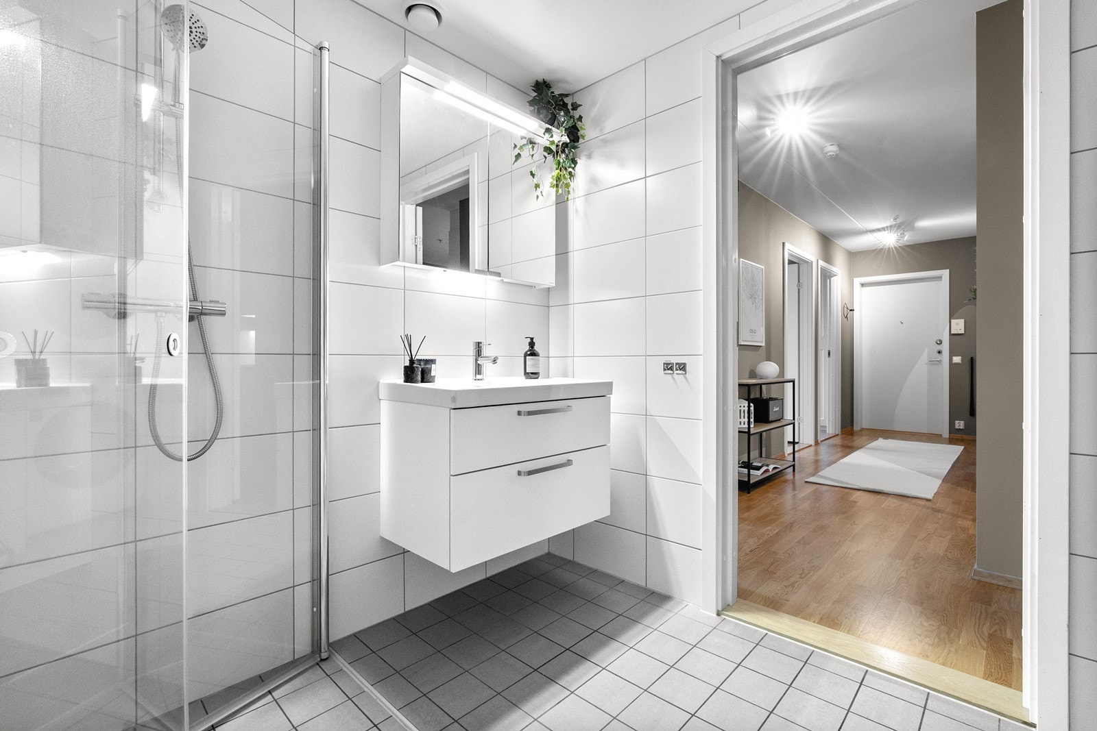Badet er innredet med vegghengt klosett, servant nedfelt i innredning, speilskap med lys og dusjhjørne med svingbare glassdører. Galleribilde