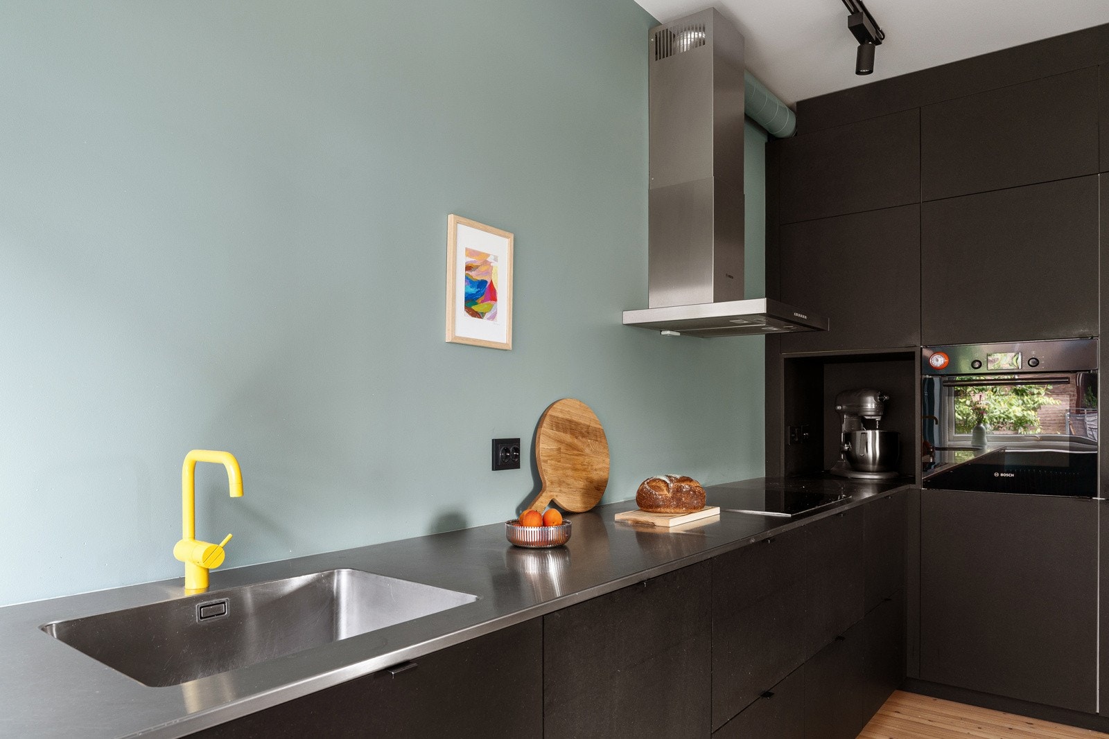 Kjøkkenet en lekker ventilatorhette i rustfritt stål over stekesonen med avtrekk ført til felles ventilasjonskanal. Galleribilde