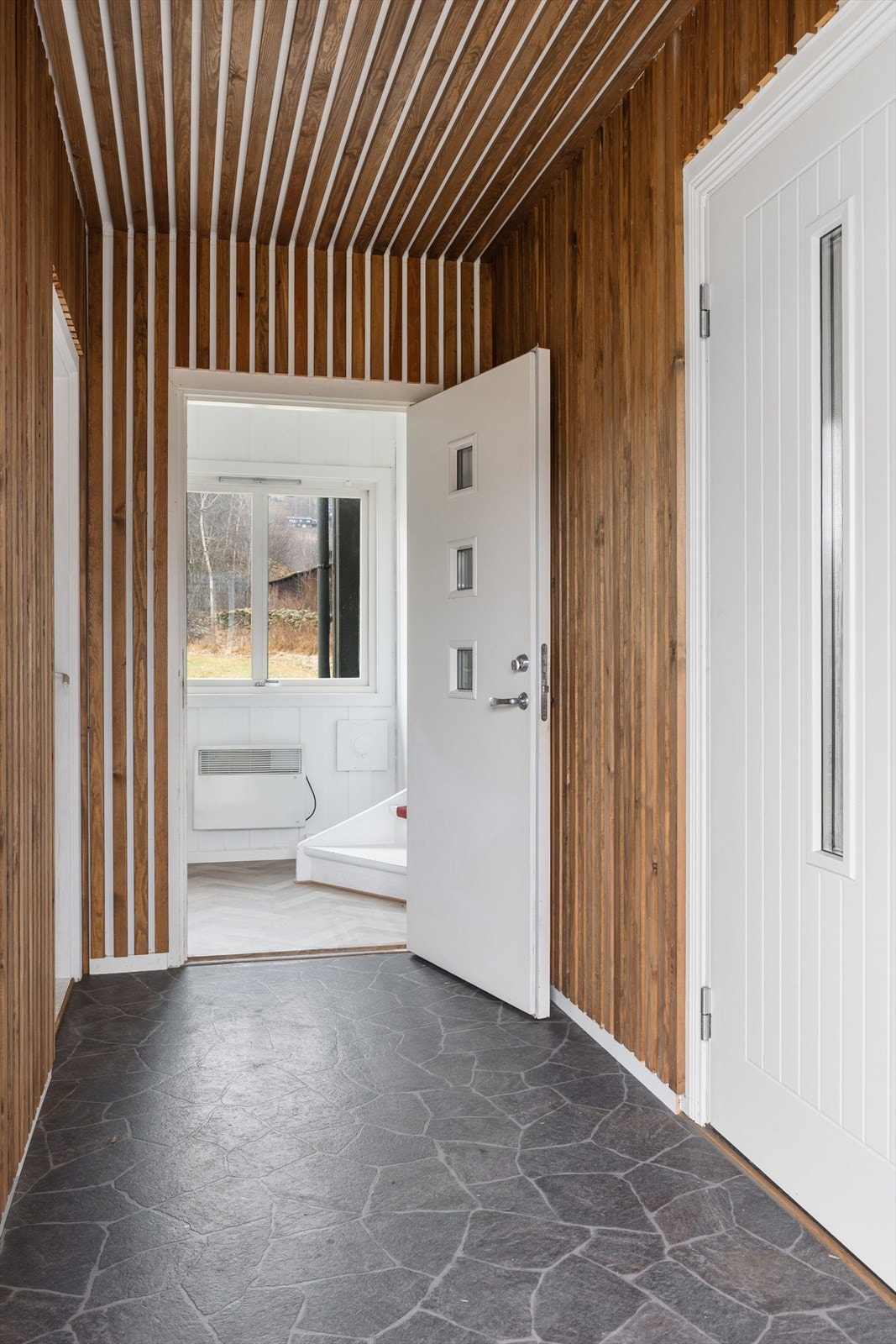 Fra entréen er det dør inn til hovedetasjen og separat inngang/trapp opp til andre etasje. Galleribilde