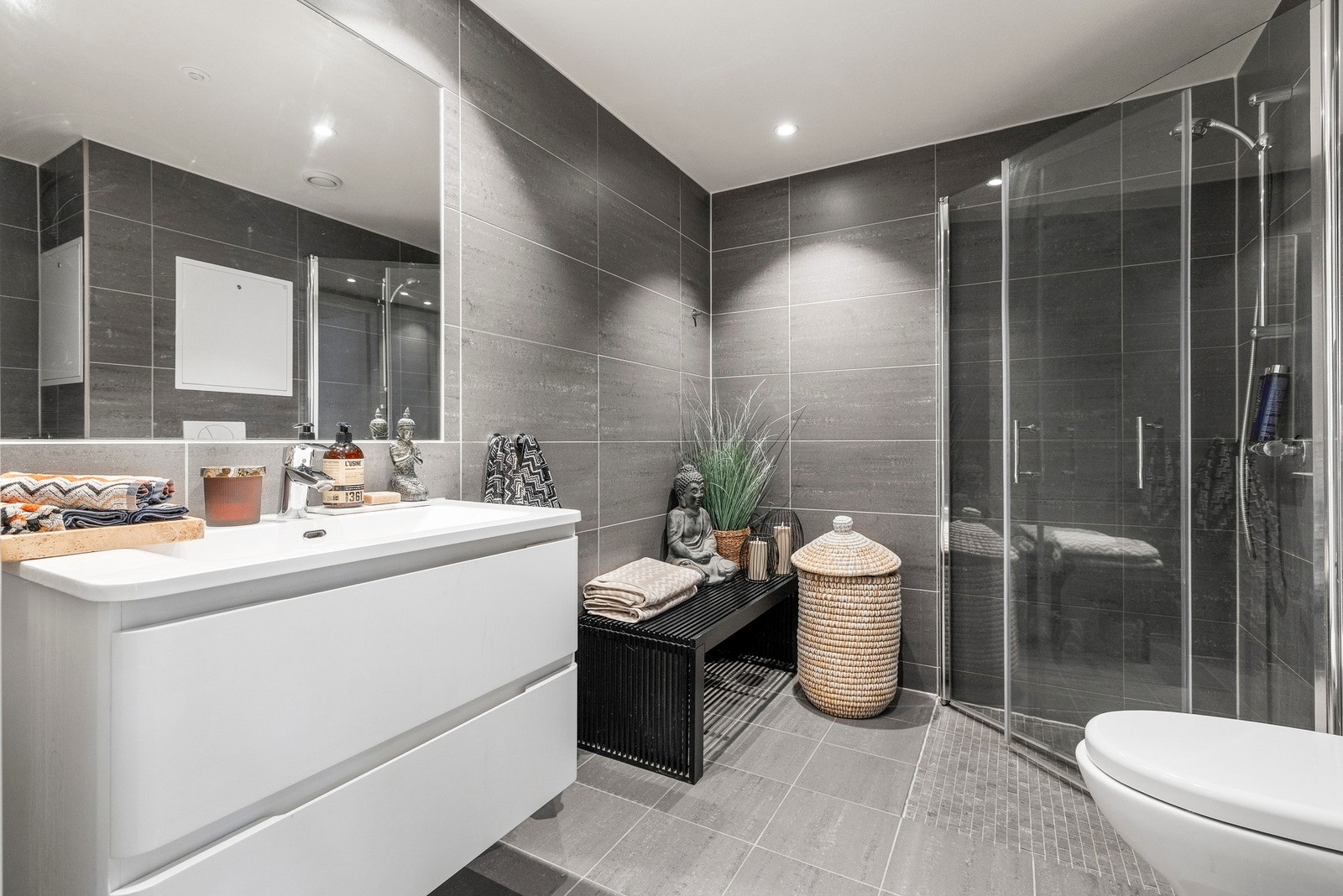 - Badet har elektriske varmekabler, vegghengt toalett med innebygd sisterne kasse, servant på vegghengt servantskap og vegghengte dusjdører i glass - Galleribilde