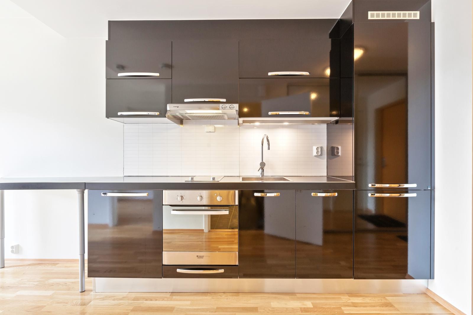 Lekkert kjøkken med integrerte hvitevarer som komfyr, oppvaskmaskin og kombiskap. Galleribilde