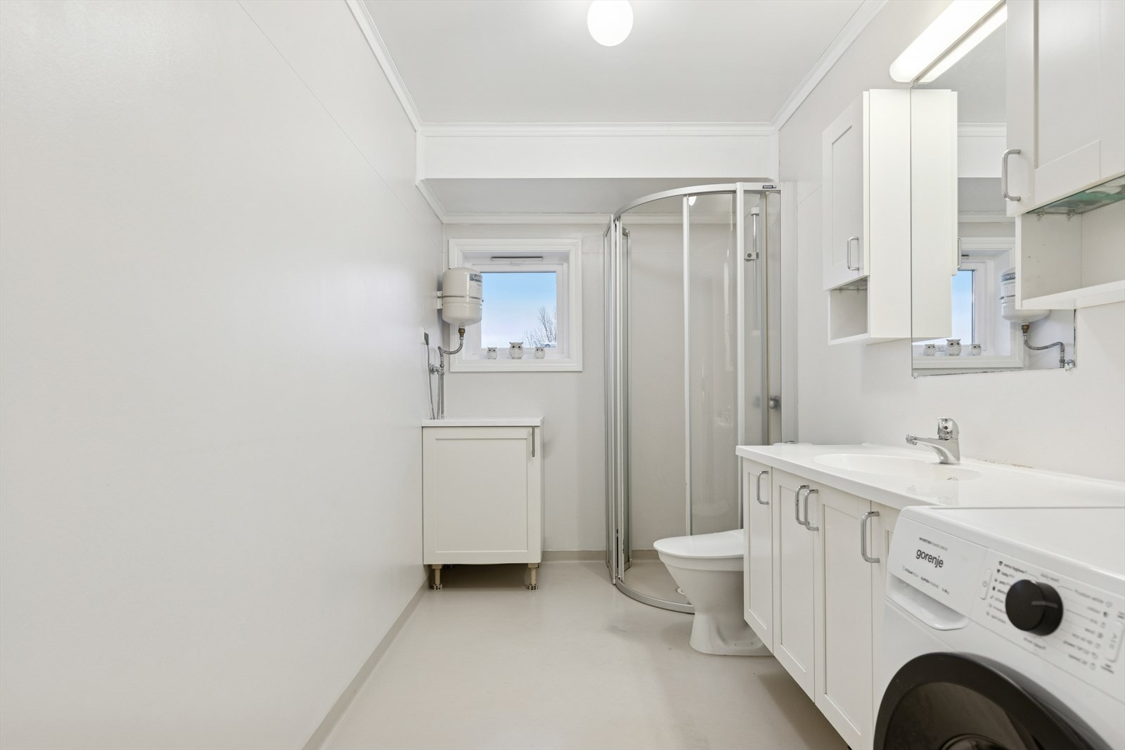 Badet er innredet med dusjhjørne, innredning med servant og toalett. Galleribilde