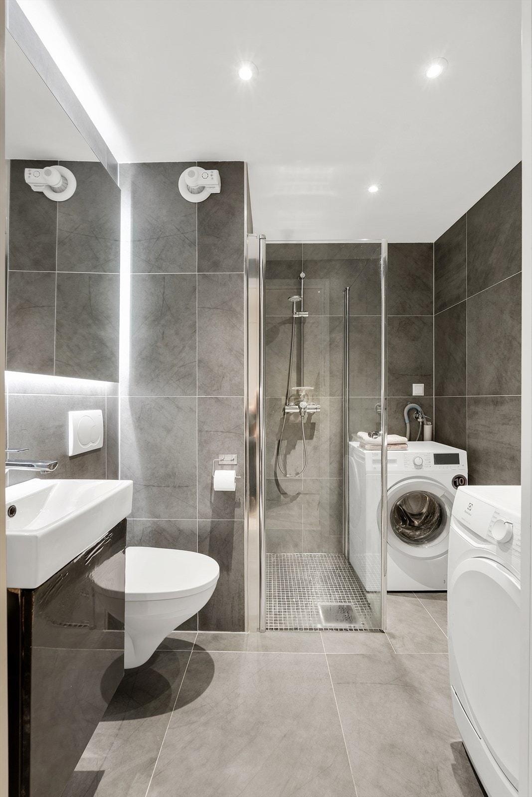 Delikat dusjhjørne med svingdører, samt opplegg for vaskemaskin og tørketrommel. Galleribilde