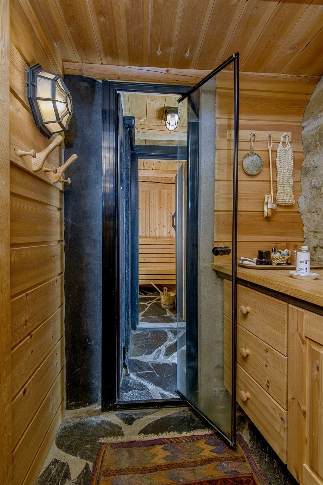 Her kombineres trepanel, gråsteinsmur og skiferlagt gulv for å skape en rustikk stil som inviterer til ro og velvære. Galleribilde