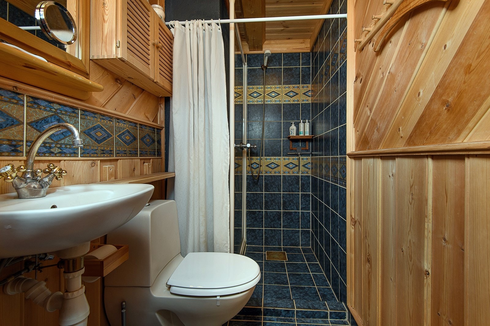 Badene i loftetasjen pene fliser dekorert med border med gullfargede detaljer, som skaper en harmonisk helhet. Galleribilde