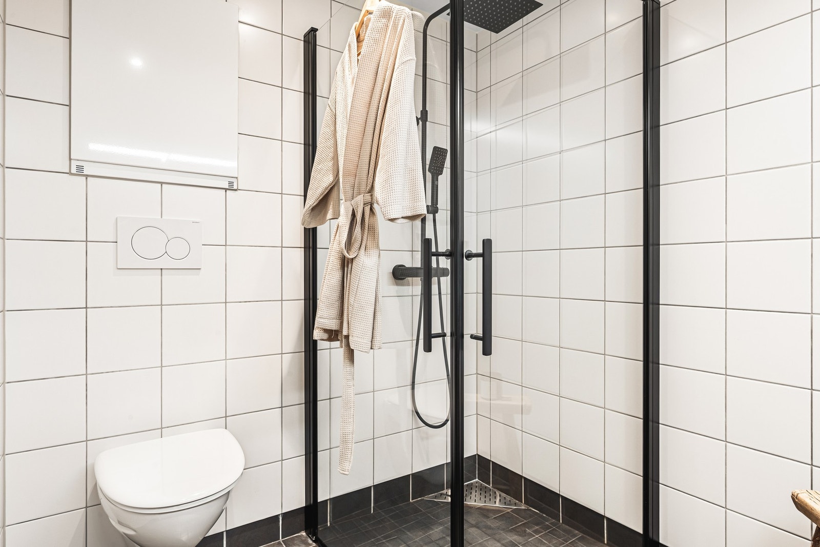 Badet er innredet med dusj med glassvegger, vegghengt toalett og baderomsinnredning. Galleribilde