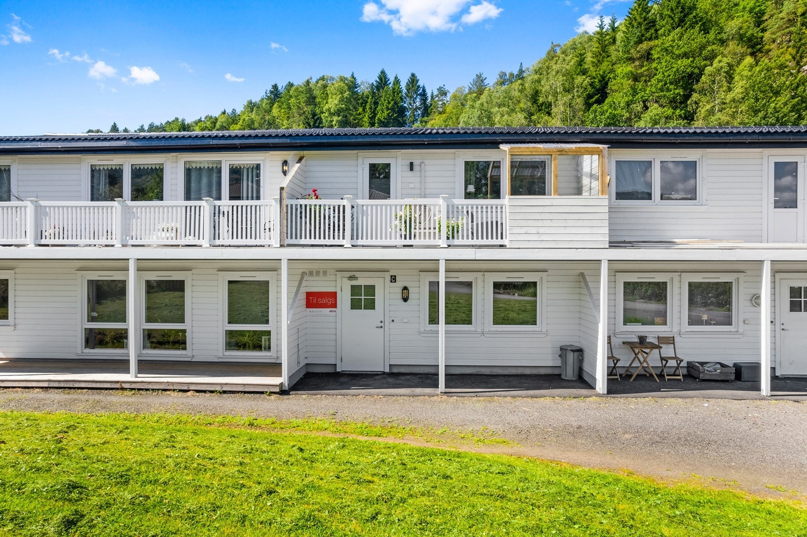 Fellesarealer er pent opparbeidet med gressplen og gruslagt parkeringsplass like ved inngangsdør. Galleribilde