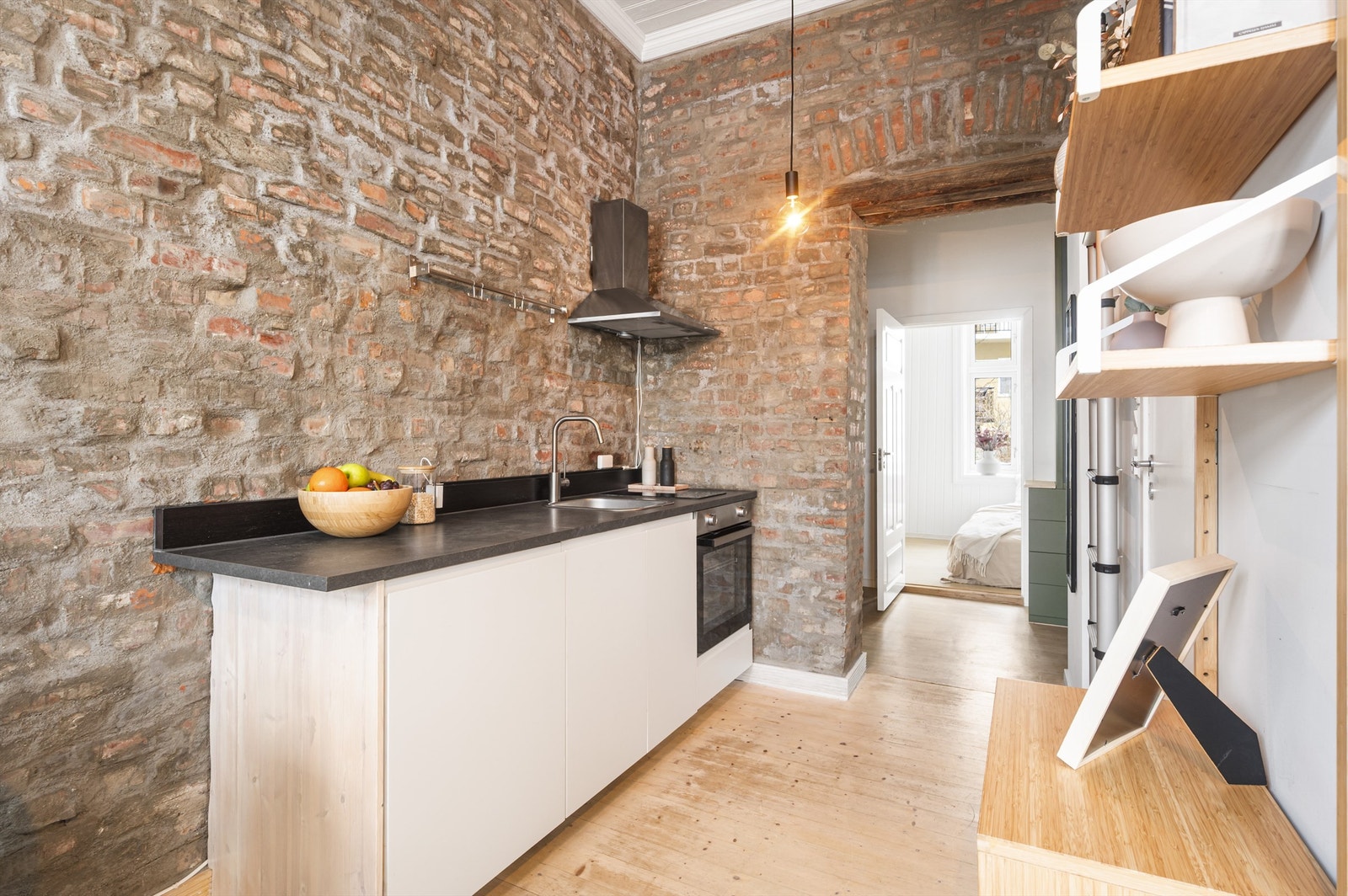 Stilrent kjøkken med funksjonell utforming. Den åpne løsningen mot stuen gir en sosial og åpen atmosfære, perfekt for både hverdagsbruk og hyggelige sammenkomster, hvor du enkelt kan underholde gjester samtidig som maten tilberedes. Galleribilde