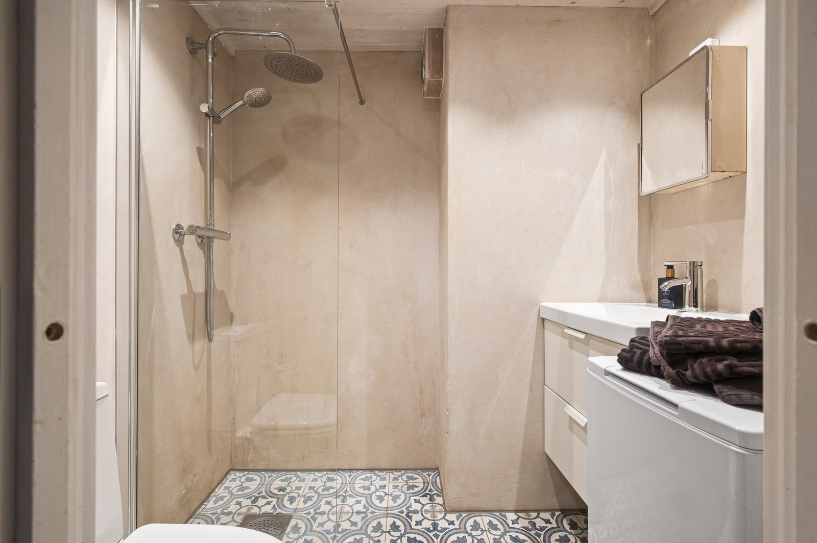 Pent og gjennomført bad, med elektriske varmekabler i gulv som gir ekstra komfort i hverdagen. Rommet er innredet i delikate fargetoner, med vegger i mikrosement og lekre, historiske fliser i terrazzomarmor. Galleribilde