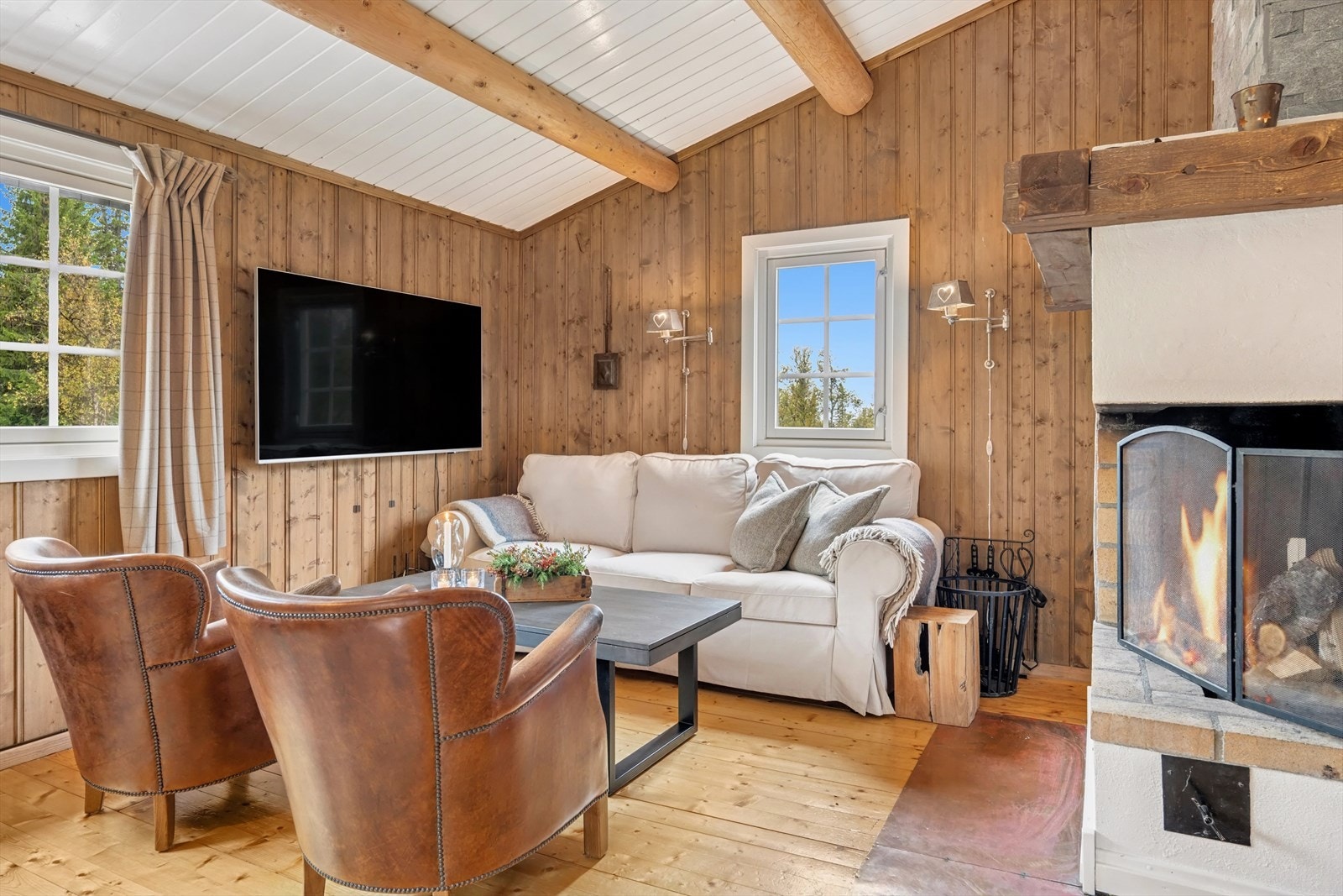 Murt åpen peis og med større vedovn i tilknytning er strategisk plassert midt i rommet og sørger for ekstra god temperatur og knitrende hygge på kalde vinterkvelder. Galleribilde