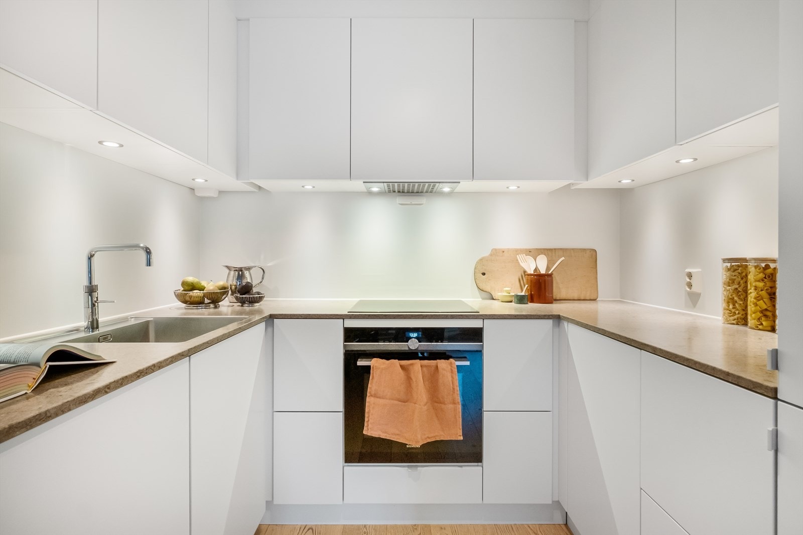 Stilrent Kvik-kjøkken fra 2020 med lyse fronter, i åpen løsning mot stuen. Her får du svært god oppbevaringsplass og en romslig arbeidsflate på en flott benkeplate i kompositt. Galleribilde