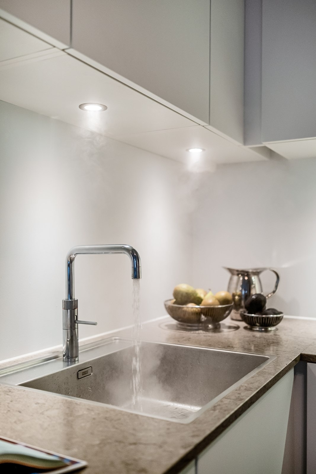 Armatur fra Quooker gir kokende vann rett fra springen. Over benkeplaten er det montert praktisk belysning, samt mekanisk avtrekk over kokeplassen. Galleribilde