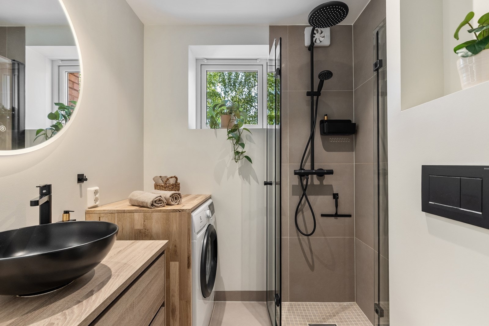 Det er varme i gulvflisene samt en praktisk nisje av tre med plass til vaskemaskinen Galleribilde