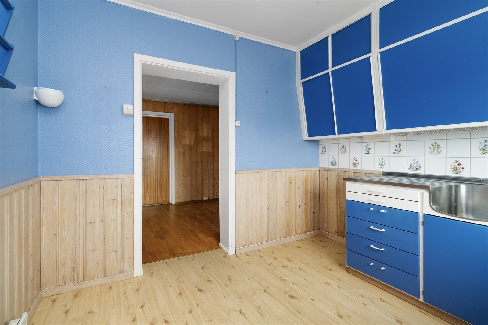 Det er avsatt plass til frittstående hvitevarer som komfyr og kjøl/fryseskap, og over kokesonen er det ventilator med avtrekk ut på vegg. Galleribilde