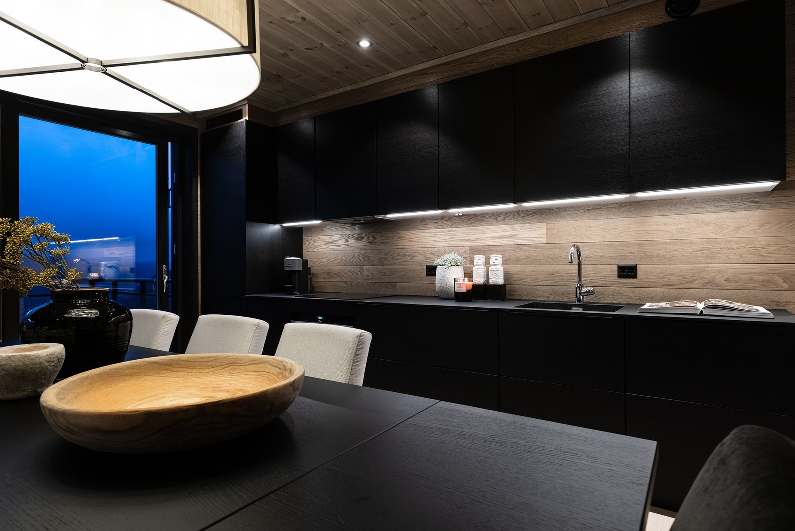 Raffinert stemning i mørke toner i det åpne kjøkkenet. Galleribilde