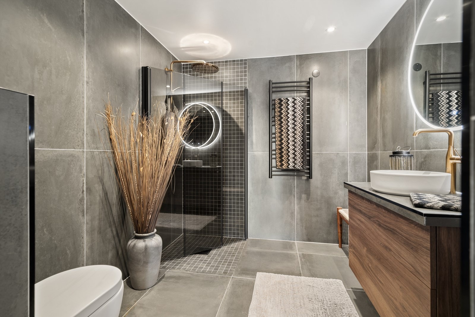 Lekkert flislagt bad består av servant med innredning, dusjhjørne med innsvingbare dører og vegghengt toalett. Galleribilde